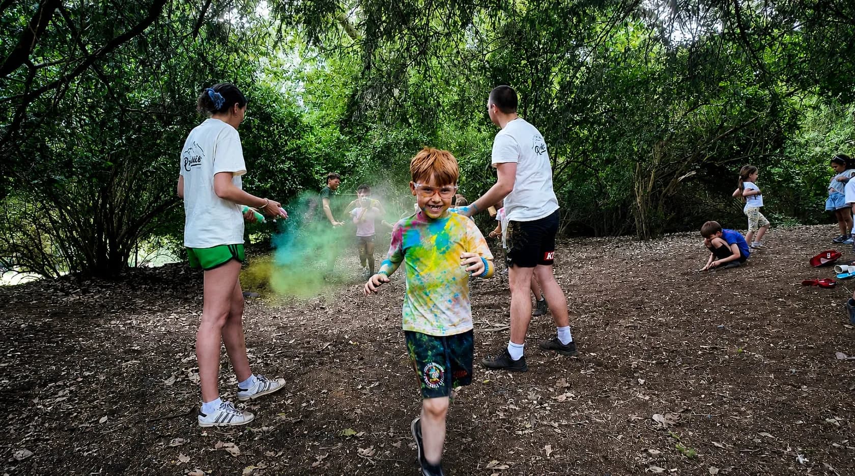 A camper covered in colour powder during a game in the woods at an Archie's camp