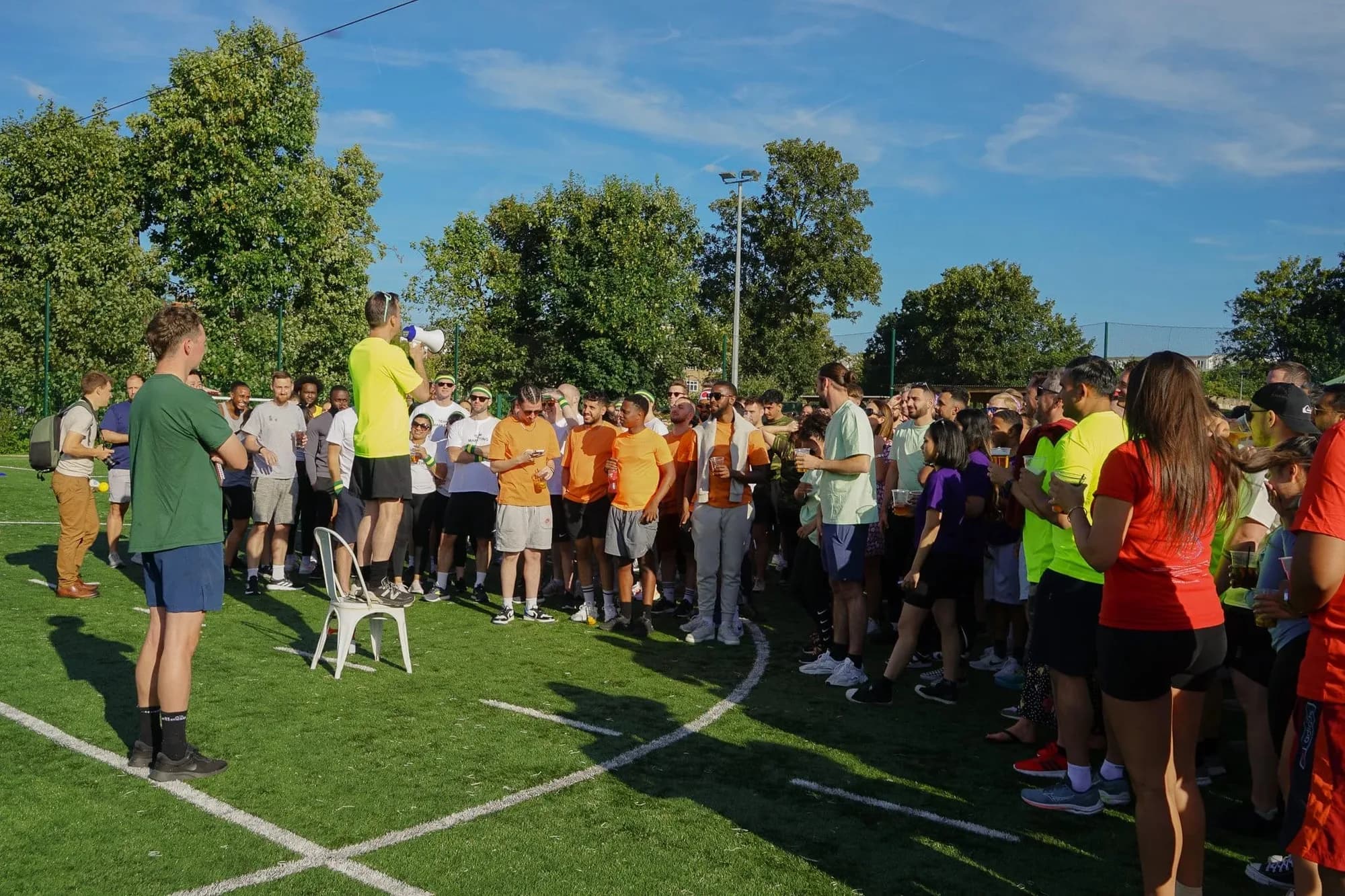 A large group gathered outdoors on a sunny day listening to a briefing