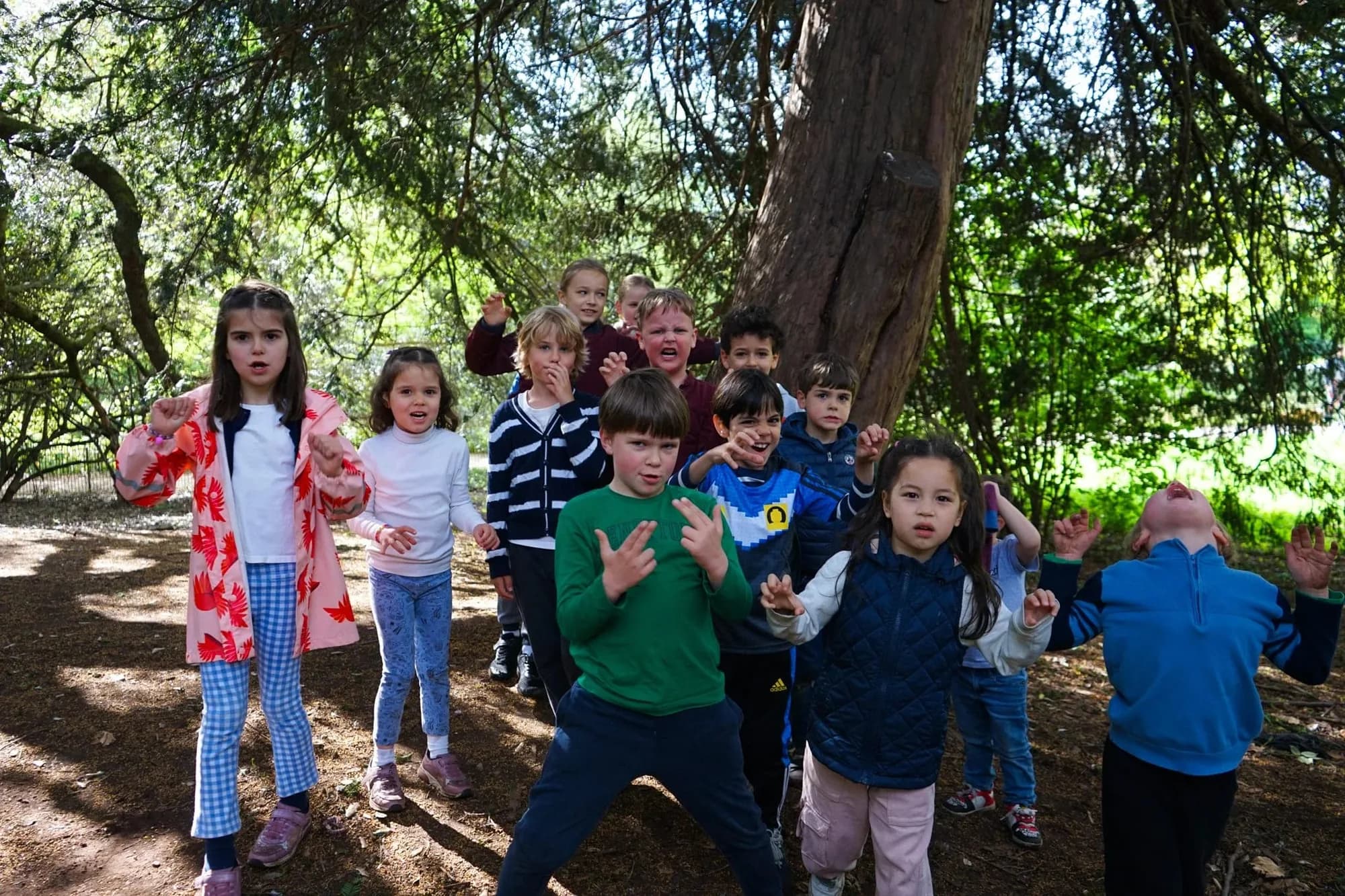 Group of children in a forest making playful gestures at Battersea camp