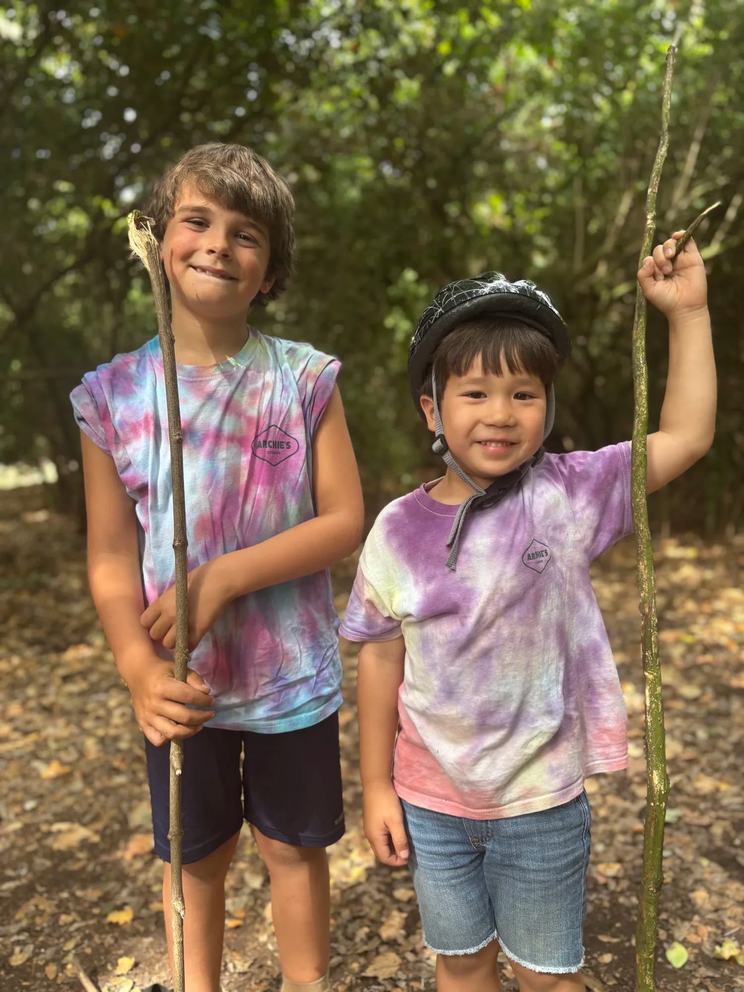 Two kids showing off their tie-dye t-shirts in the woods