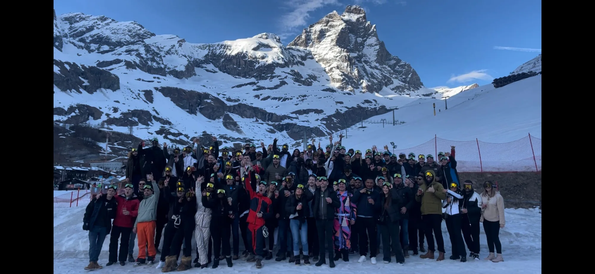 A large group in winter clothing and ski goggles on a corporate ski trip