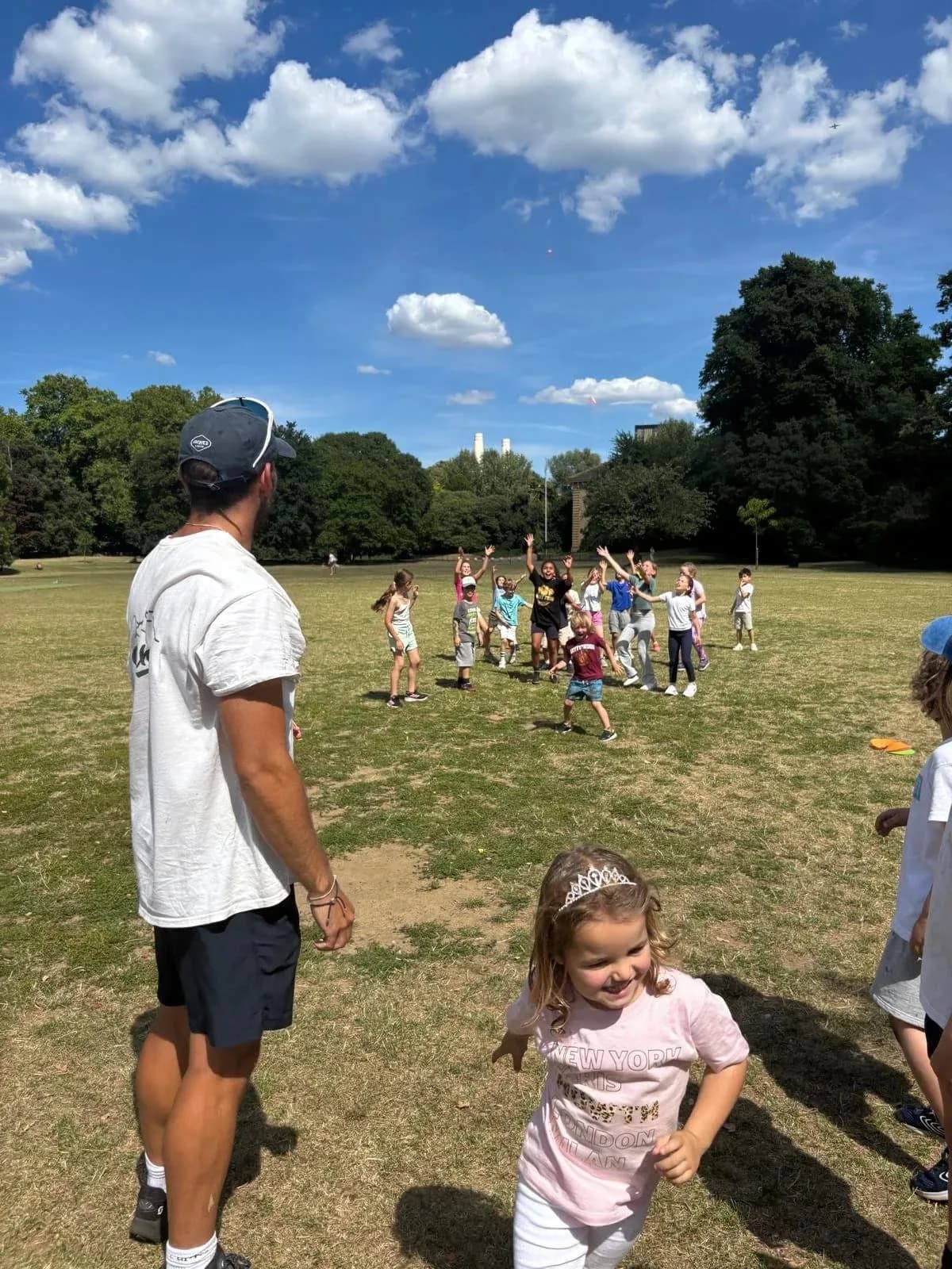 Children playing and running in Battersea Park on a sunny day